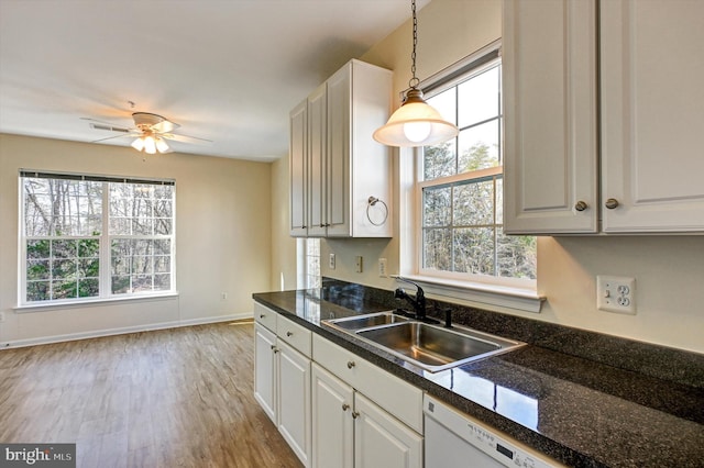 kitchen featuring pendant lighting, light wood-type flooring, sink, and white cabinets