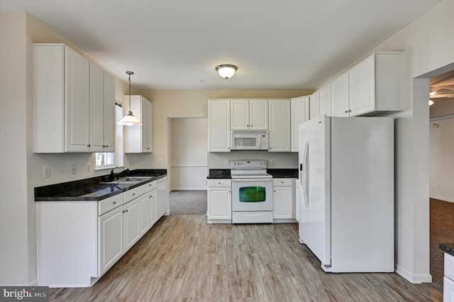 kitchen with sink, white appliances, hanging light fixtures, and white cabinets