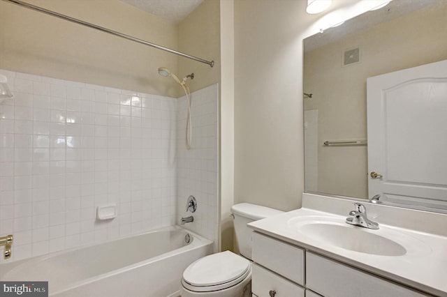 full bathroom featuring vanity, tiled shower / bath combo, and toilet