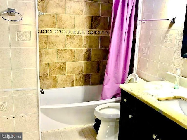 full bathroom featuring shower / bath combination with curtain, vanity, toilet, and tile walls