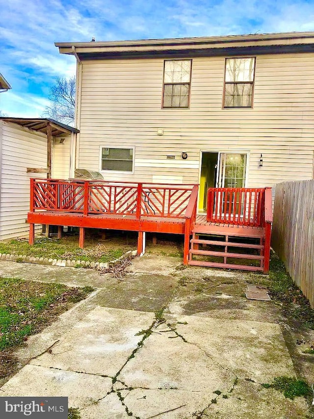 back of property featuring a wooden deck and a patio