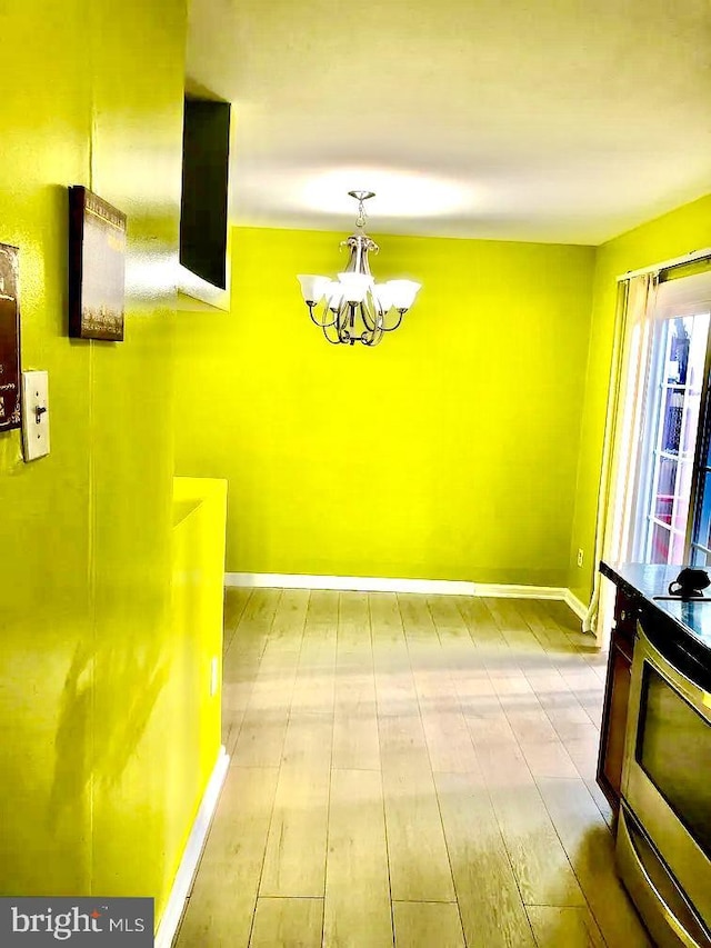 unfurnished dining area featuring a notable chandelier and light hardwood / wood-style floors