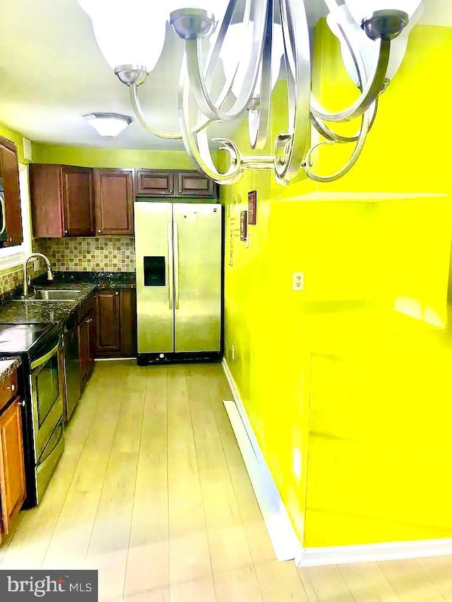 kitchen featuring sink, backsplash, electric range, stainless steel fridge with ice dispenser, and light wood-type flooring