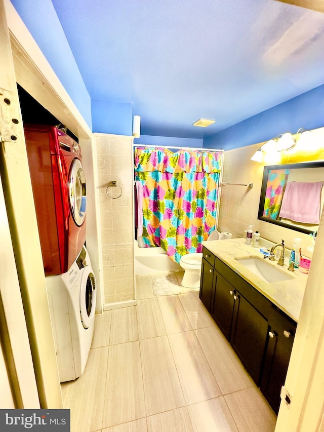 full bathroom featuring shower / tub combo with curtain, tile patterned flooring, vanity, stacked washer and clothes dryer, and toilet