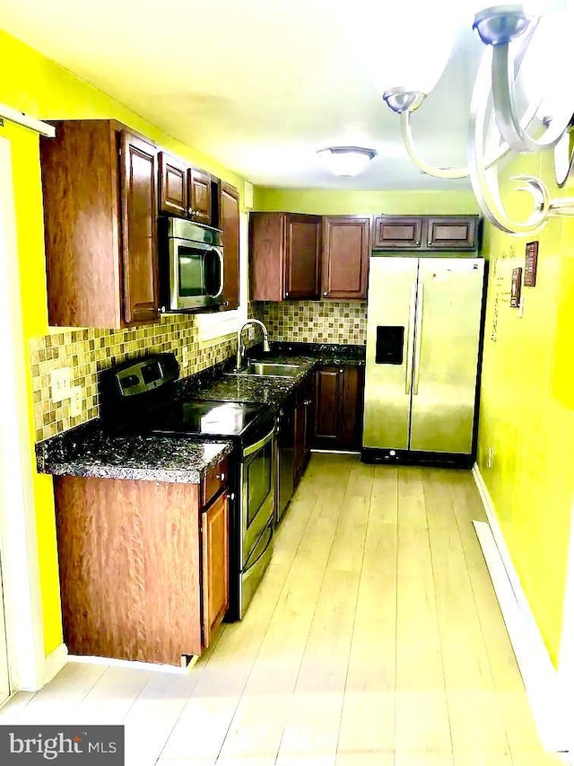 kitchen with sink, decorative backsplash, stainless steel appliances, and dark stone counters