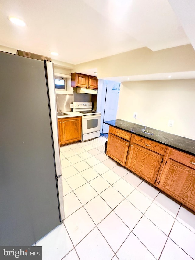 kitchen featuring electric stove, sink, stainless steel refrigerator, and light tile patterned flooring