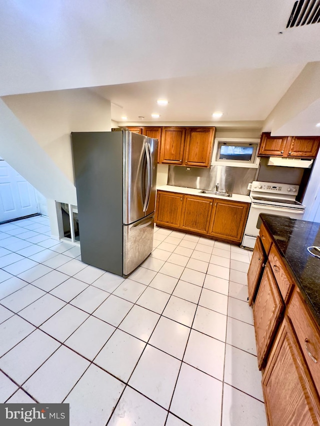 kitchen with light tile patterned flooring, white electric range, stainless steel fridge, and sink