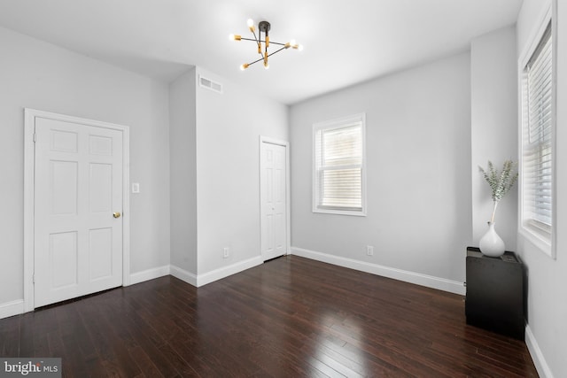 unfurnished bedroom with an inviting chandelier, dark hardwood / wood-style flooring, and a closet