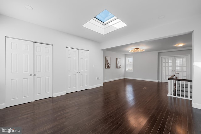 unfurnished living room featuring a skylight, dark hardwood / wood-style floors, and french doors