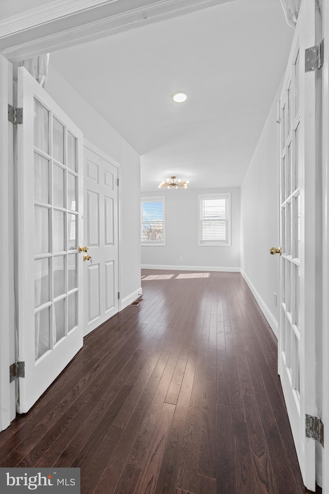 empty room featuring dark hardwood / wood-style flooring and a notable chandelier