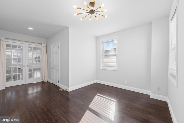 unfurnished room with dark hardwood / wood-style flooring, french doors, and a chandelier