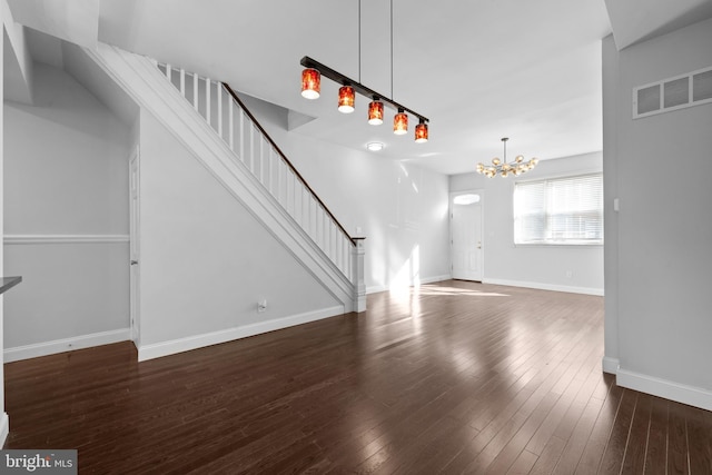 unfurnished living room featuring dark wood-type flooring and a notable chandelier