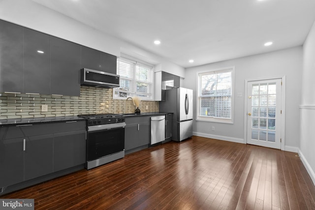 kitchen with sink, gray cabinetry, dark hardwood / wood-style flooring, stainless steel appliances, and decorative backsplash