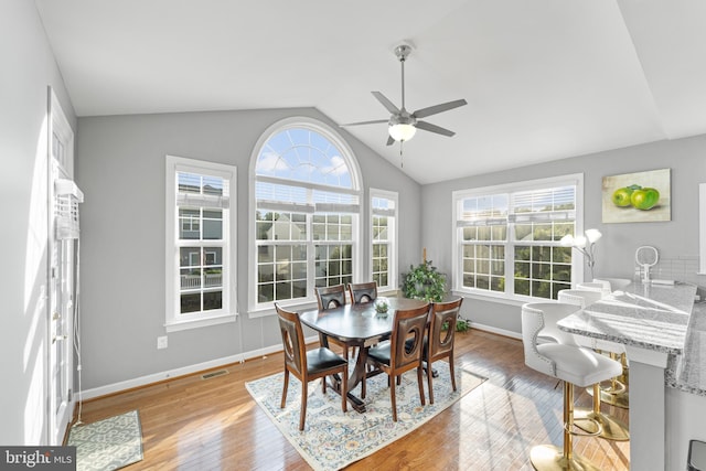 dining area with ceiling fan, vaulted ceiling, and light hardwood / wood-style flooring