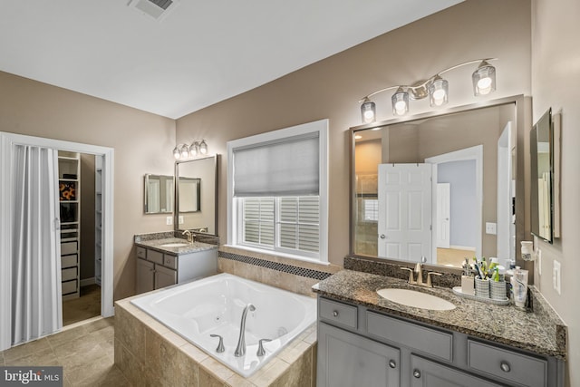 bathroom with vanity, a relaxing tiled tub, and tile patterned floors