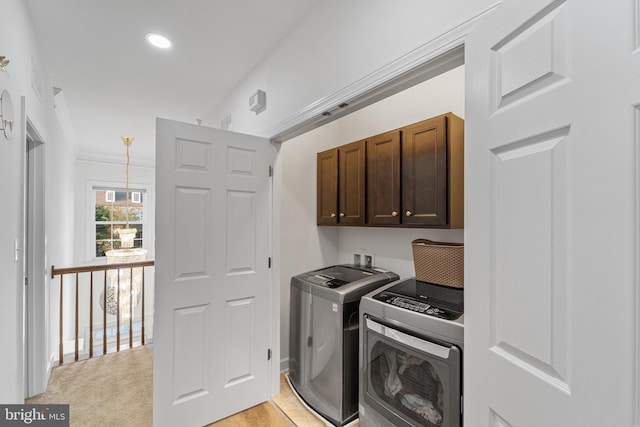 washroom featuring cabinets, ornamental molding, washer and dryer, and light colored carpet