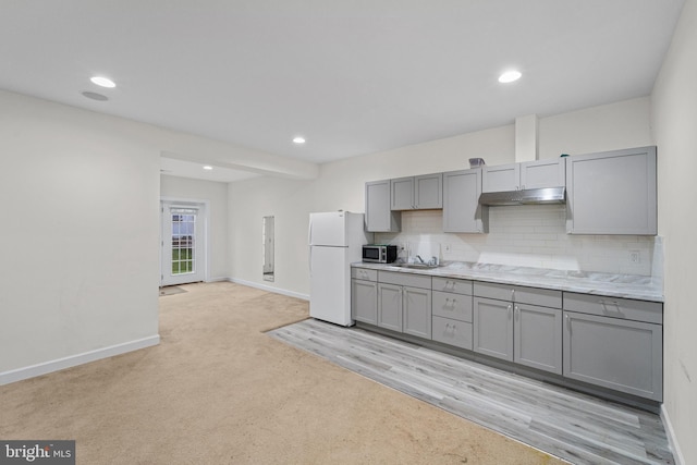 kitchen featuring sink, gray cabinets, backsplash, white refrigerator, and light colored carpet