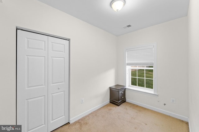 unfurnished bedroom featuring light colored carpet and a closet