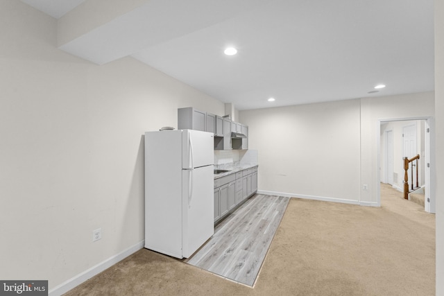 kitchen with white refrigerator, gray cabinets, and light carpet