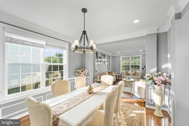 dining room with a notable chandelier, ornamental molding, and hardwood / wood-style floors