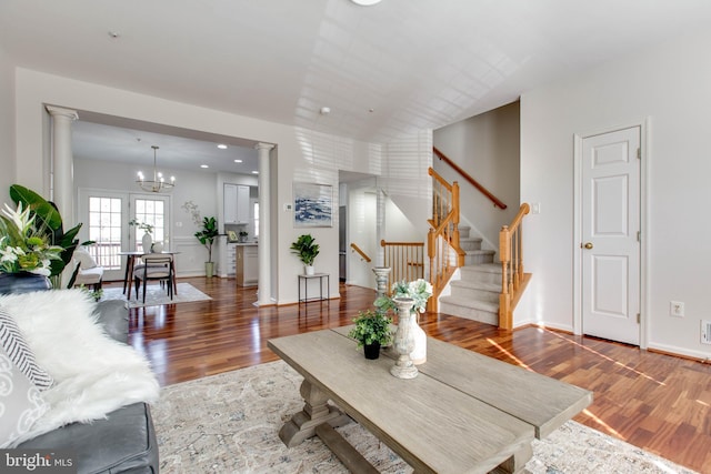 living room with an inviting chandelier, dark wood-type flooring, and decorative columns