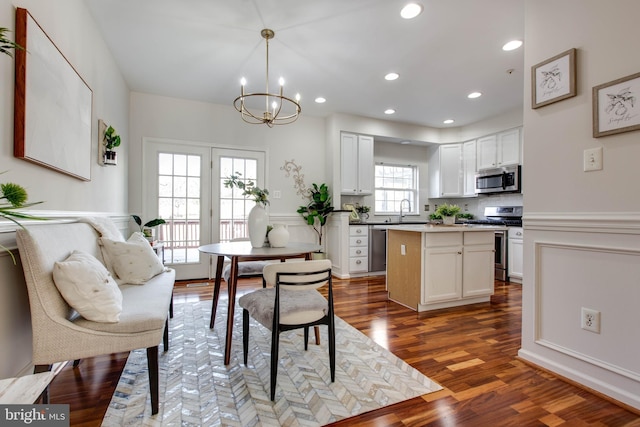 kitchen with a center island, light wood-type flooring, appliances with stainless steel finishes, pendant lighting, and white cabinets