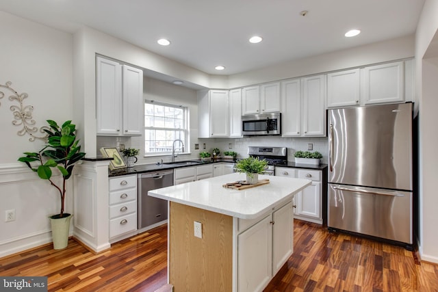 kitchen with dark wood-type flooring, sink, white cabinetry, a center island, and stainless steel appliances