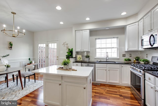 kitchen with pendant lighting, sink, white cabinets, and appliances with stainless steel finishes