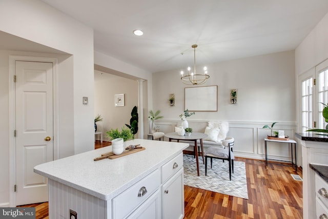 kitchen featuring white cabinetry, light hardwood / wood-style floors, hanging light fixtures, and a kitchen island