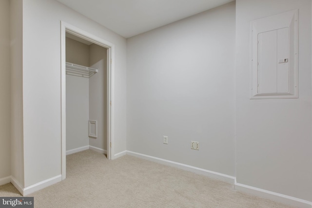 unfurnished bedroom featuring a closet, electric panel, and light carpet