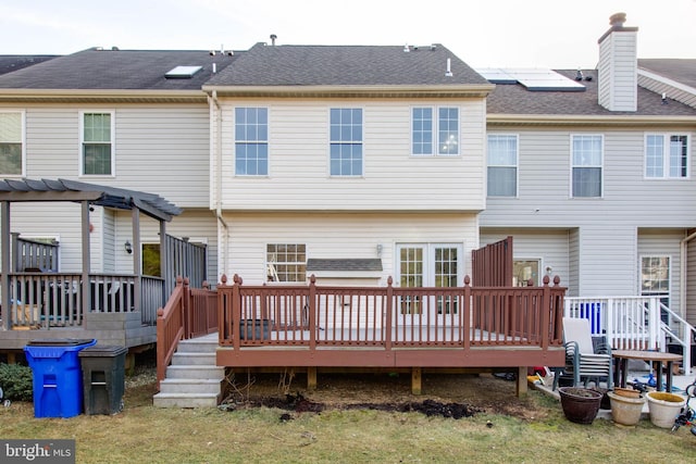 back of house featuring a wooden deck and solar panels