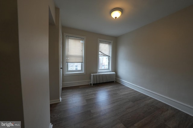 empty room with dark wood-type flooring and radiator