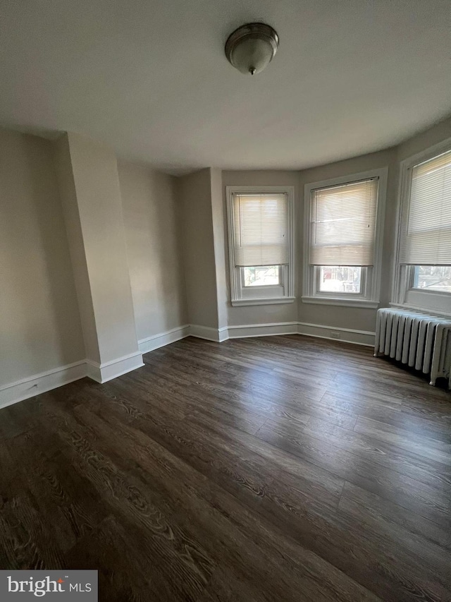 empty room featuring dark wood-type flooring and radiator