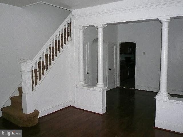 stairs with hardwood / wood-style flooring and decorative columns