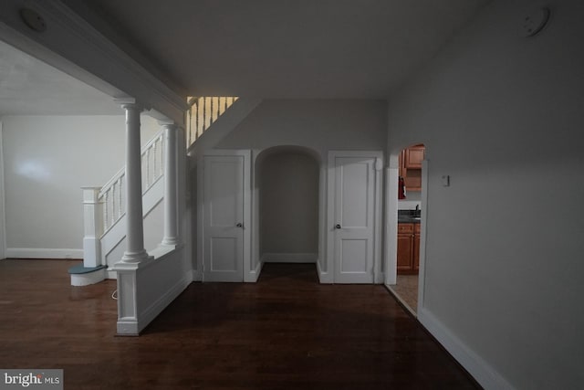 hallway with ornate columns and dark hardwood / wood-style floors