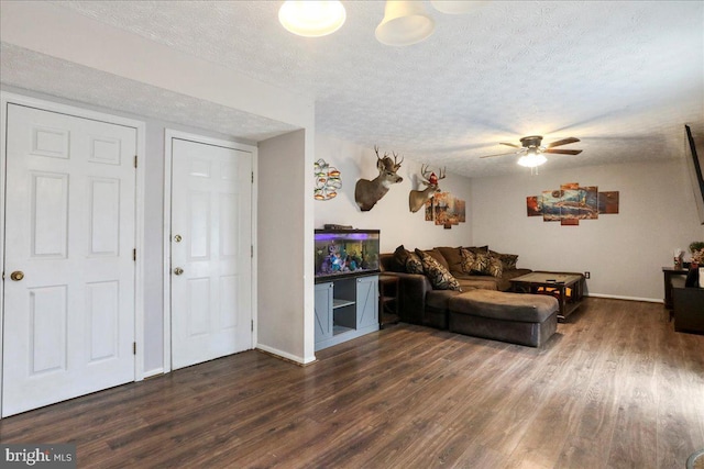 living room with ceiling fan, dark wood-type flooring, and a textured ceiling