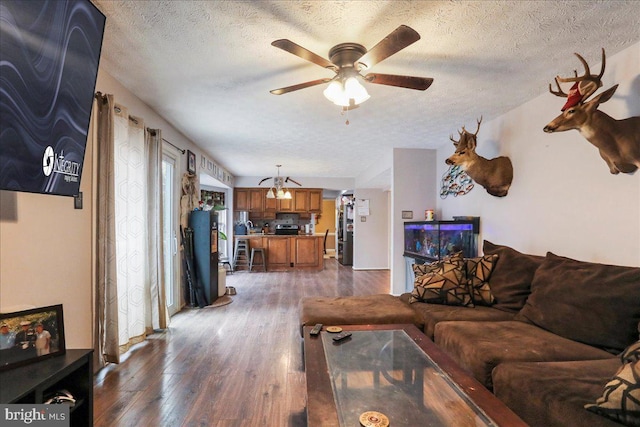 living room with ceiling fan, dark wood-type flooring, and a textured ceiling