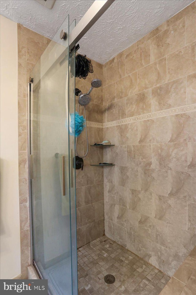 bathroom featuring an enclosed shower and a textured ceiling