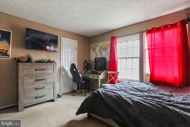 bedroom with light colored carpet and a textured ceiling