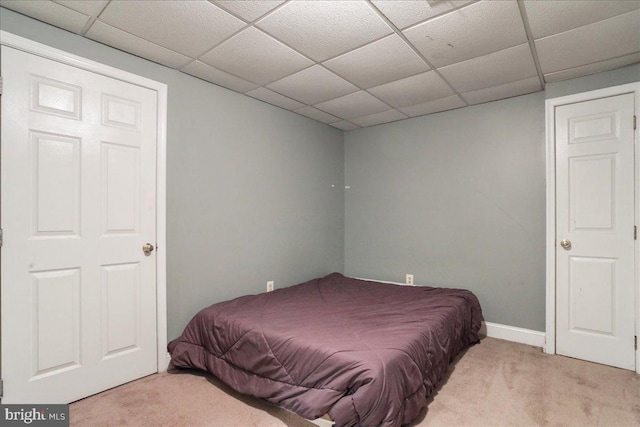 bedroom with light colored carpet and a drop ceiling