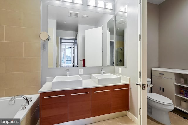 bathroom with a relaxing tiled tub, vanity, tile patterned floors, and toilet