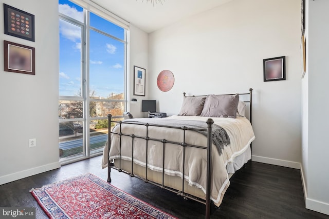 bedroom featuring expansive windows and dark hardwood / wood-style floors