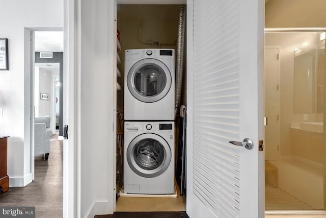 laundry area featuring stacked washing maching and dryer and dark hardwood / wood-style flooring