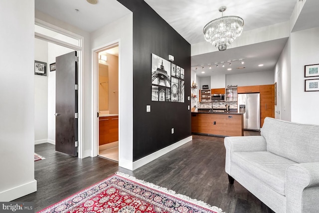 interior space with dark hardwood / wood-style floors, track lighting, and a notable chandelier