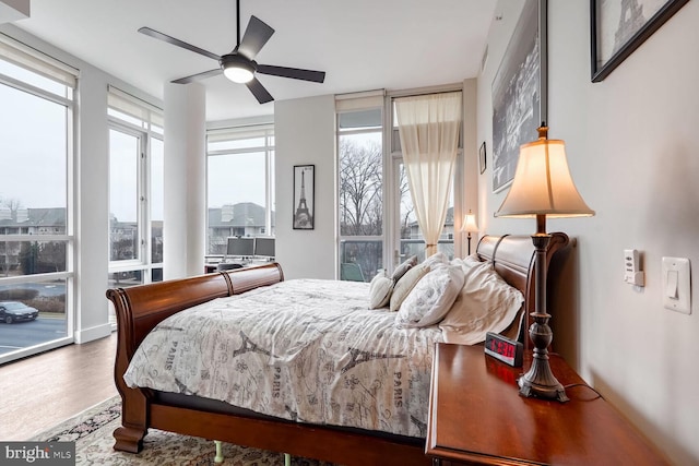 bedroom with ceiling fan, hardwood / wood-style floors, and a wall of windows