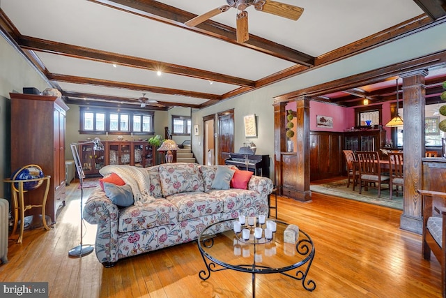 living room featuring beam ceiling, light hardwood / wood-style flooring, ceiling fan, and ornate columns