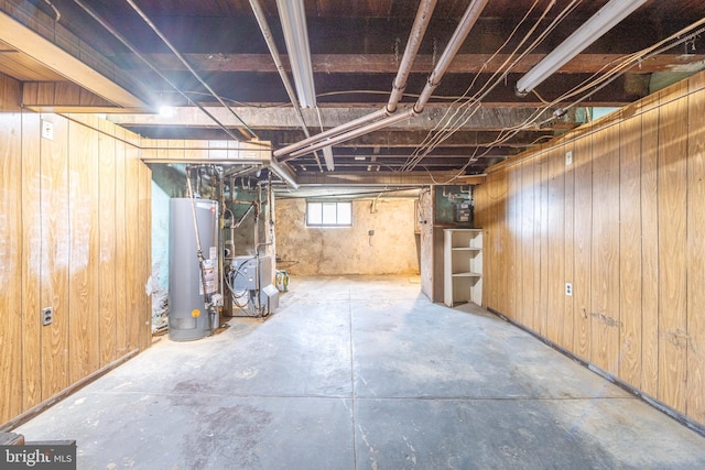 basement featuring water heater and wood walls