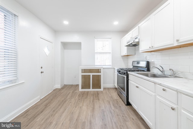 kitchen with white cabinetry, stainless steel gas range oven, sink, and tasteful backsplash