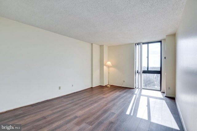 empty room with floor to ceiling windows, a textured ceiling, baseboards, and dark wood-style flooring