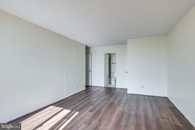 empty room featuring baseboards, dark wood-type flooring, and a textured ceiling